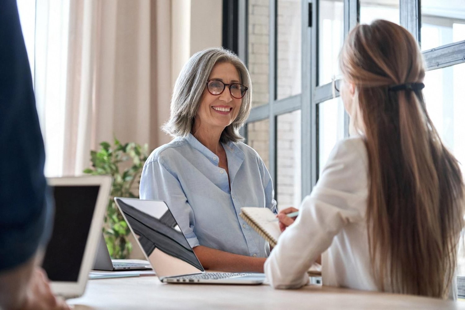 Senior compliance officer discussing due diligence findings with an analyst in a UAE meeting room