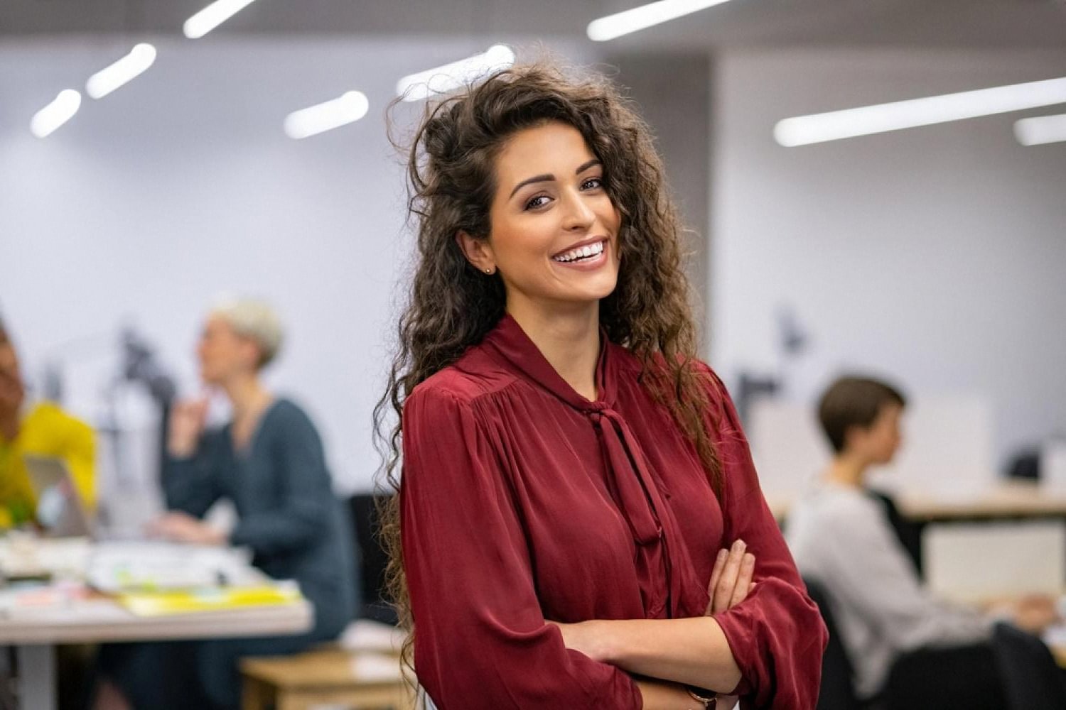 Corporate investigator smiling in a Dubai office where colleagues review compliance files